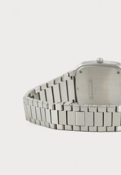 Stainless steel watch with a rectangular case, brushed finish, and link bracelet. Features a textured back and subtle brand engraving.