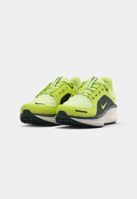 Limoengroene sportschoenen met een gequiltde textuur, zwarte accenten en een dikke witte tussenzool. Beschikt over een gemusterde rubberen buitenzool en vetersluiting.