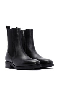 Bottines en cuir noir avec panneaux élastiques sur les côtés, fermeture éclair latérale, bout arrondi et talon block. Texture lisse et design minimaliste.