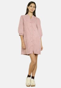 Abito button-up rosa con colletto alto, maniche a sbuffo e una vestibilità ampia. Texture liscia, lunghezza al ginocchio con una leggera fessura frontale.