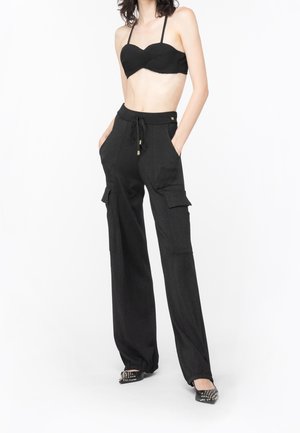 Haut de bikini noir à côtes avec des fines bretelles, associé à un pantalon cargo noir taille haute présentant des poches latérales, un cordon de serrage et une coupe évasée.