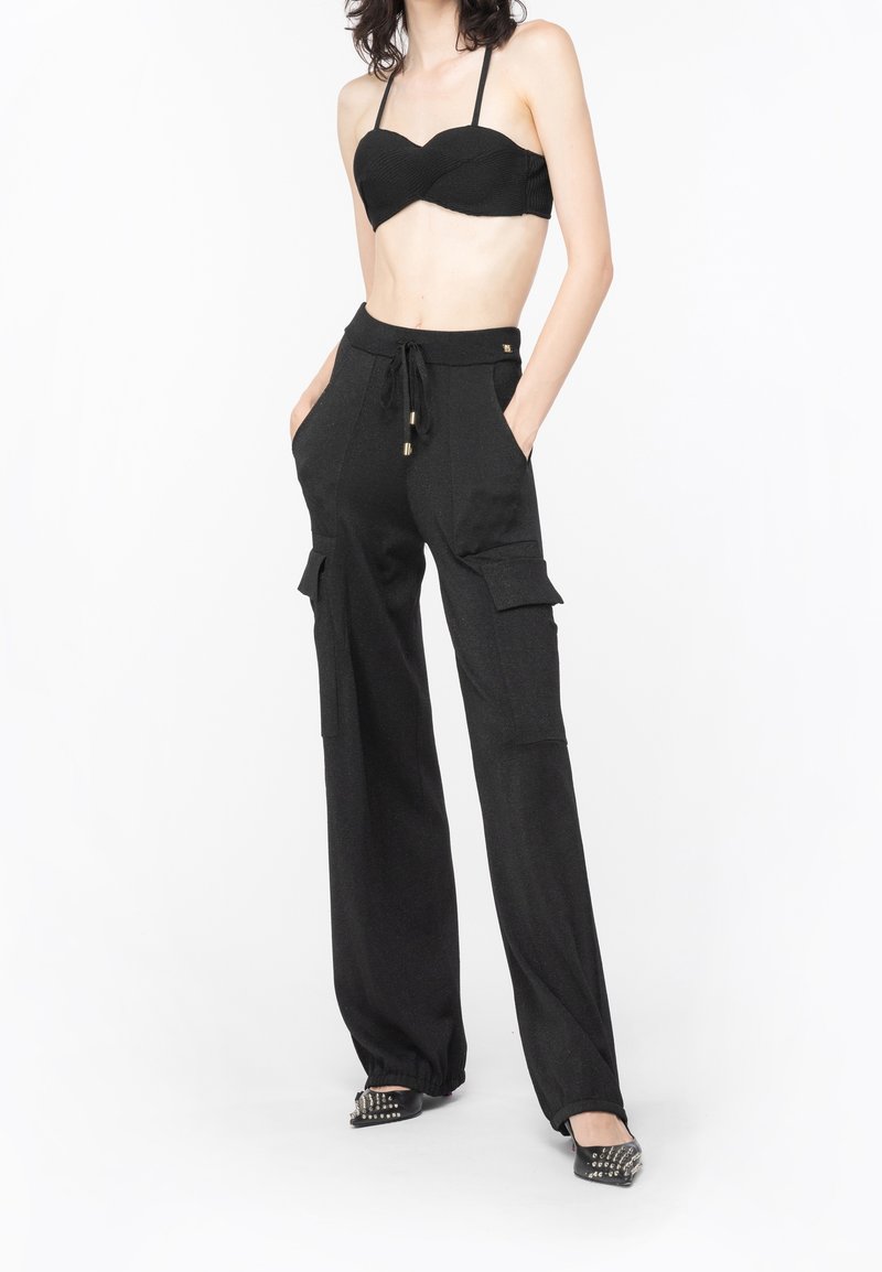 Zwart geribbelde bikini-top met dunne bandjes, gecombineerd met hoog-getailleerde zwarte cargobroek met zijzakken, trekkoord en een uitlopende design.