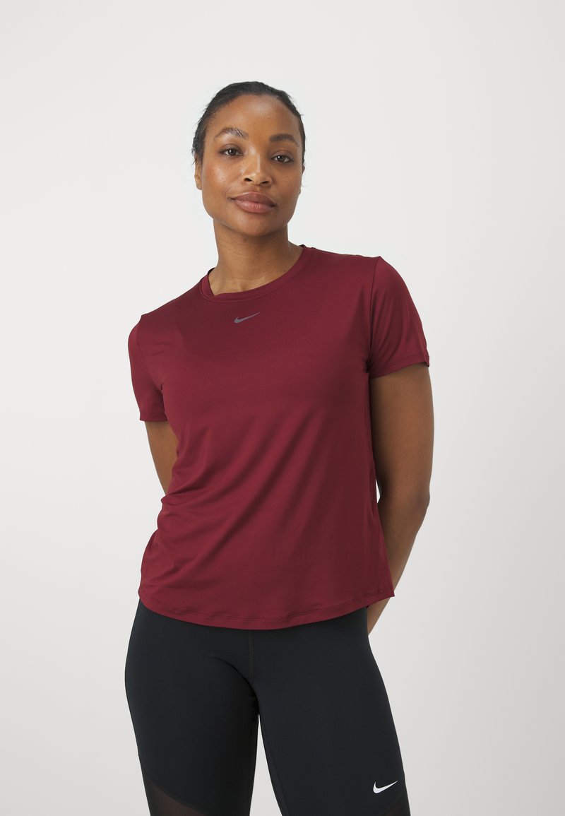 T-shirt de sport bordeaux à manches courtes avec un col rond et un petit logo Nike gris au centre. Tissu lisse, coupe décontractée.