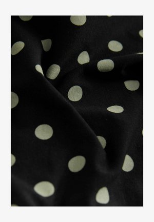 Fekete, sima tapintású szövet, nagy, krémszínű pöttyökkel, amelyek véletlenszerű mintázatban helyezkednek el.