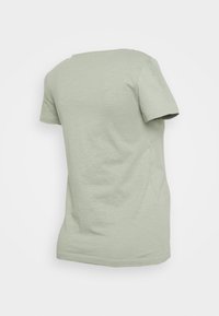 T-shirt verde claro de manga curta com decote redondo e tecido suave e texturizado. Design simples e minimalista sem padrões ou detalhes.