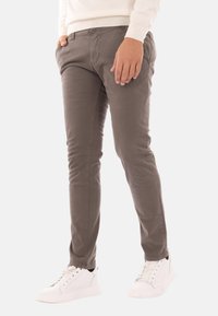 Chinos grey in cotone con una vestibilità slim, dotati di tasche laterali e una texture liscia, abbinati a sneakers bianche.