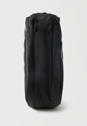 Schwarze, weiche, vertikale Reisetasche mit zwei Reißverschlussfächern vor einem einfarbigen hellen Hintergrund.