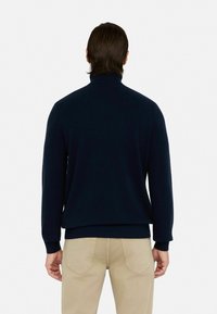 Granatowy sweter z golfem, z prążkowanymi mankietami i dolnym wykończeniem, wykonany z miękkiego materiału. Charakteryzuje się luźnym krojem i minimalnymi detalami.