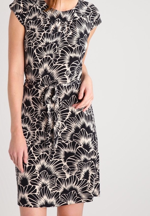 Robe noire avec un motif floral crème. Manches courtes, encolure ronde et détail de taille cintrée avec un nœud. Tissu lisse avec une silhouette légèrement ajustée.