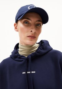 Felpa navy con logo frontale, tessuto testurizzato e coulisse, abbinata a un cappellino navy con testo bianco e visiera curve.