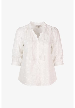 Witte katoenen blouse met bloembroderie, knoopsluiting aan de voorkant, franjes en driekwartmouwen. Heeft een gerimpelde kraag en manchetten.