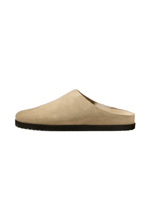 Mule beige en daim, à enfiler, avec bout fermé et semelle plate en caoutchouc noir.