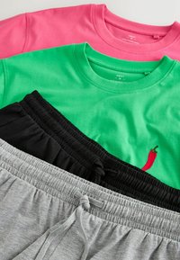 T-shirts à col rond roses et verts associés à des shorts noirs et gris à taille élastique, le t-shirt vert présentant un petit motif de piment rouge.