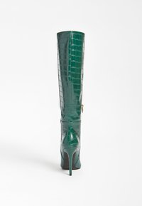 Botas de charol verde hasta la rodilla con textura de cocodrilo, tacón de aguja esbelto y detalle de cremallera lateral.