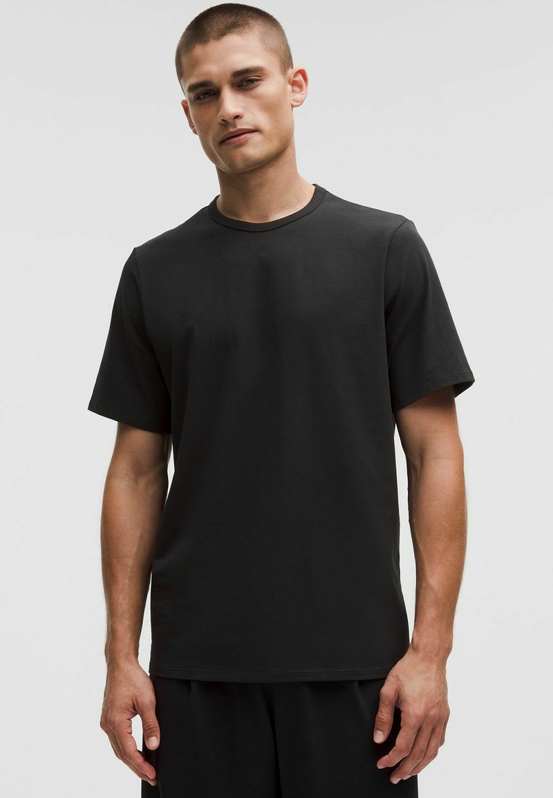 Svart bomull T-shirt med korta ärmar, rund halsringning och avslappnad passform. Slät textur, minimalistisk design, inga synliga logotyper eller mönster.