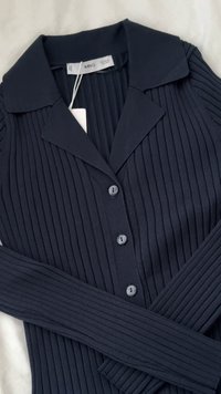 Cardigan a coste blu navy con colletto, chiusura a cinque bottoni anteriori e maniche lunghe. Texture morbida con finitura liscia. Etichetta attaccata.