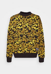 Sudadera negra con un patrón dorado en espiral, hecha de una tela suave, con puños y dobladillo acanalados, y una etiqueta en la parte inferior izquierda.
