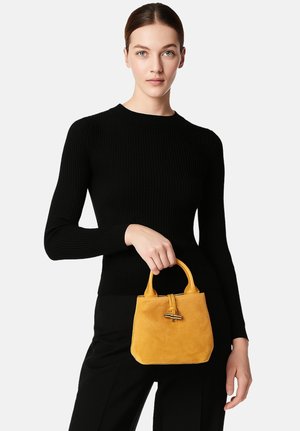 Wildleder-Handtasche in Gelb, mit einer strukturierten Form, zwei kurzen Griffen und einem dekorativen Hardware-Akzent auf dem Deckel.