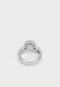 Anillo de plata con una banda redondeada y un diseño decorativo en forma de corona en la parte superior. Textura suave, acabado pulido y detalles sencillos.