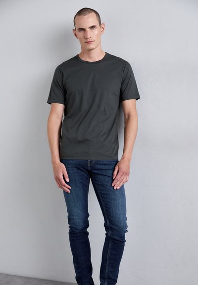 Tricou scurt cu mânecă, de culoare gri închis, dintr-un material neted, asortat cu blugi blue denim ajustați. Design simplu, fără modele sau accente vizibile.
