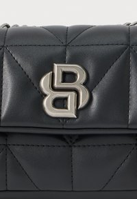 Μαύρη δερμάτινη τσάντα χειρός με καπιτονέ σχέδιο, διαθέτει μεταλλικό κούμπωμα με σχέδιο λογότυπου που αλληλοσυνδέεται. Λείος υφής με εμφανή ραψίματα.