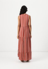 Robe maxi en rouille avec des rayures verticales blanches, sans manches, design en plusieurs niveaux, tissu fluide et col rond.