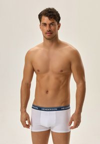 Białe bokserki męskie z granatowym pasem w talii z nazwą marki "HENDERSON". Gładki materiał o dopasowanym kroju.
