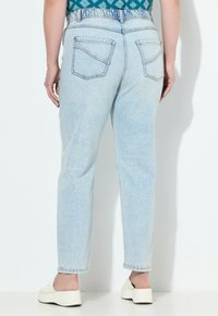 Vaaleansiniset farkut, joissa on suora lahje, kaksi takataskua ja korkea vyötärö. Farkuissa on hienovaraisia haalistumisia ja ompeluyksityiskohtia.