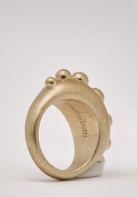 Goldfarbener Ring mit einer glatten, abgerundeten Band, das drei sphärische Akzente aufweist. Konkaves Innere mit eingraviertem Markennamen.