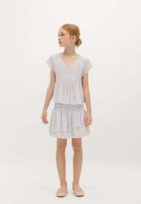Robe blanche avec un décolleté en V, de courtes manches courtes, un corsage smocké et une jupe froncée. Présente un motif floral dans des couleurs pastel.