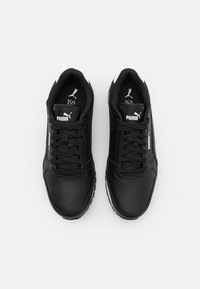 Chaussures de sport noires en cuir synthétique au design élégant, avec des lacets noirs, des touches blanches et une semelle texturée.