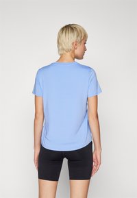 Camiseta de manga corta azul claro con cuello redondo, textura suave y corte relajado, combinada con shorts de bicicleta negros.