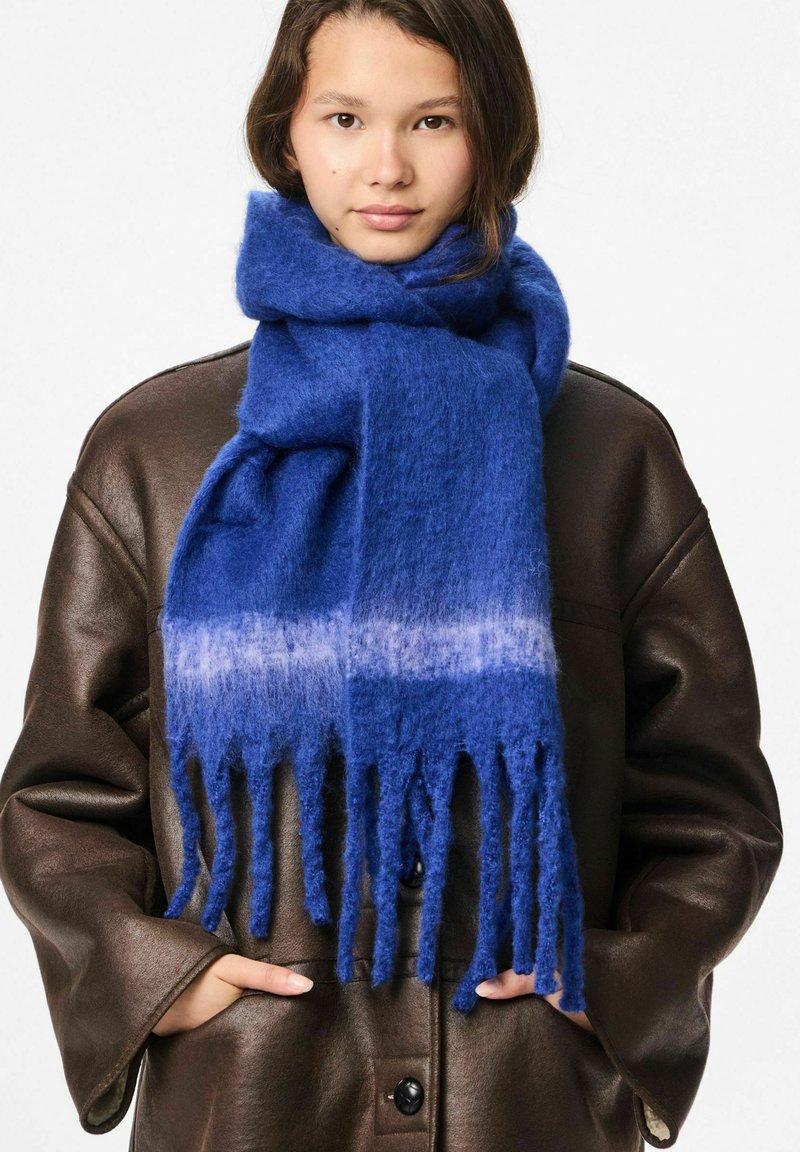 Sciarpa di lana blu con design a frange con sfumature, caratterizzata da una texture morbida e da una delicata transizione dal blu scuro a tonalità più chiare.