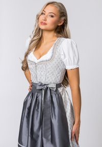 Traditional Bavarian dress featuring a patterned silver and white bodice, white puff sleeves, and a grey satin skirt with a matching bow.