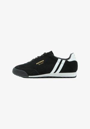 Zapatilla deportiva de ante negro con rayas blancas y suela blanca, marca dorada "Patrick Dijon" en el lateral y puntera de goma texturizada.