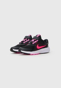 Baskets de course Nike noires et roses avec des semelles blanches, dotées de lacets roses et d'une fermeture par sangle, mises en scène sur un fond neutre.