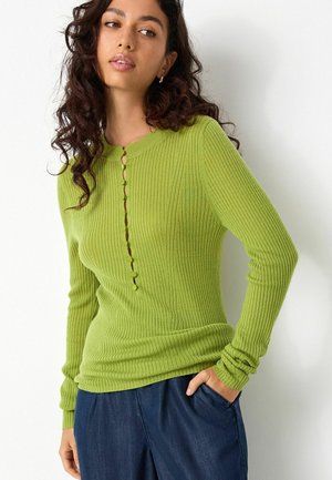 Green ribbed long-sleeve top featuring a round neck and a button-down front with six rounded buttons. The material has a soft texture.