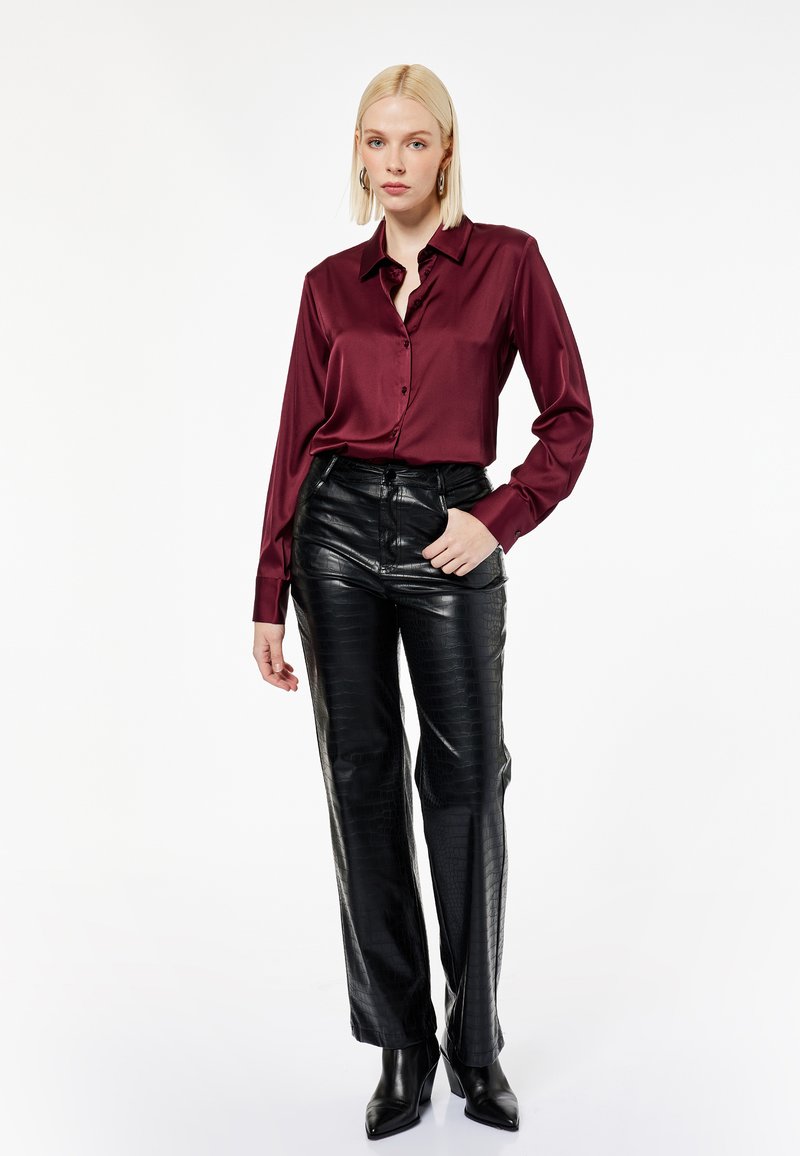 Maroon satin knap-up skjorte med lange ærmer, parret med sorte faux-krokodille læderbukser, der har et lige ben-design og høj talje.