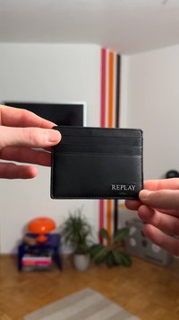 Black leather cardholder with four slots, embossed "REPLAY" logo, smooth texture, rectangular shape, and minimalistic design.