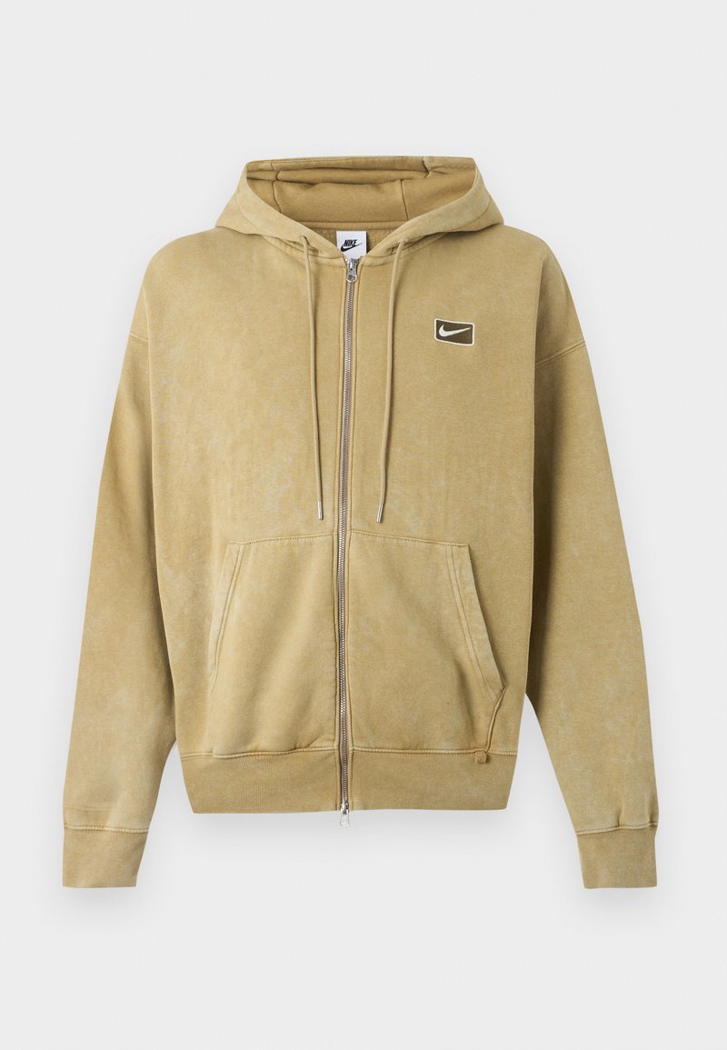 Beigefarbener Nike Hoodie mit durchgehendem Reißverschluss, Fronttaschen, Kordelzugkapuze, gerippten Bündchen und kleinem Nike Swoosh-Logo auf der Brust.