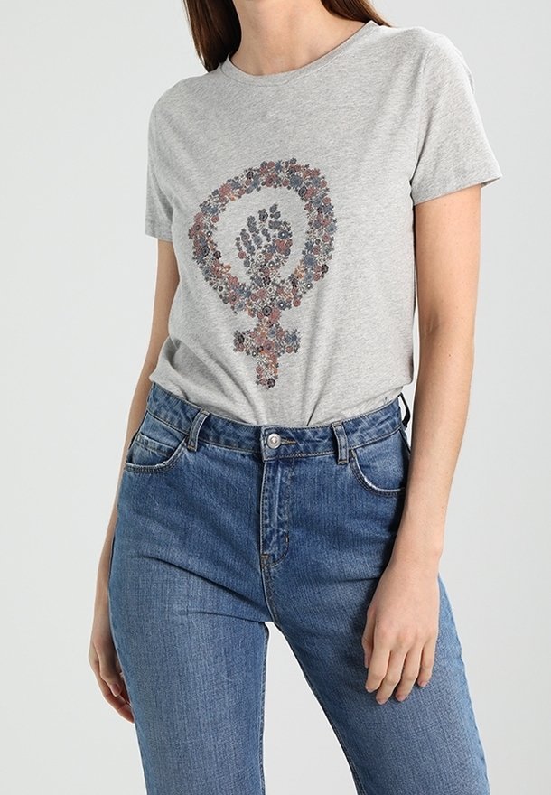 T-shirt grigia in cotone con stampa floreale a forma di simbolo femminista, abbinata a jeans in denim. Maniche corte e vestibilità classica.