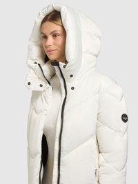 Doudoune blanche avec une grande capuche, une fermeture éclair et des boutons-pression. Présente un design matelassé et un patch logo sur la manche.