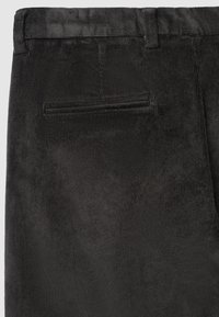 Pantalons en velours côtelé noir avec une texture à fines côtes, dotés d'une taille standard et d'une poche arrière. Tissu doux avec une finition mate.