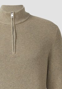 Beżowy sweter dzianinowy z wysokim kołnierzem i zamkiem. Wzór teksturowany z prążkowanymi detalami wzdłuż kołnierza i mankietów.