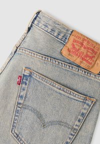 Φωτεινά γαλάζια τζιν Levi's από denim με πίσω τσέπη που έχει χαρακτηριστική ραφή, κόκκινη ετικέτα Levi's και δερμάτινη ετικέτα της μάρκας στη μέση.