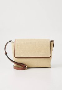 Smėlio spalvos pintinė rankinė su tekstūruota paviršiaus danga, rudos odos detalėmis, užsegamu aktu ir reguliuojamu dirželiu nešiojimui per petį.