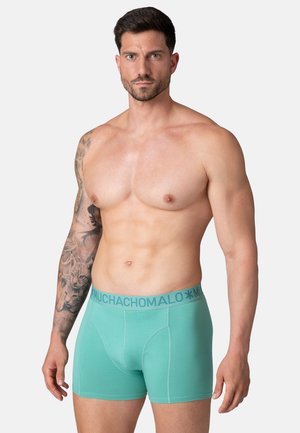 Mėtų žalios spalvos bokseriai su minkšta tekstūra, turintys kontrastingą mėlynos-pilkos spalvos elastingą juostą, ant kurios išspaustas užrašas "MUCHACHO".