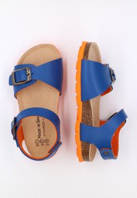 Sandales bleues avec semelle en liège et semelle en caoutchouc orange. Caractéristiques de deux sangles réglables avec une boucle métallique. Texture lisse et mate.