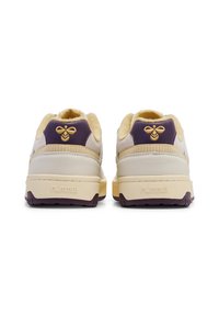 Baskets beiges et violettes avec une finition texturée. Présente un logo sur le talon et une semelle bicolore. Doublure jaune doux.