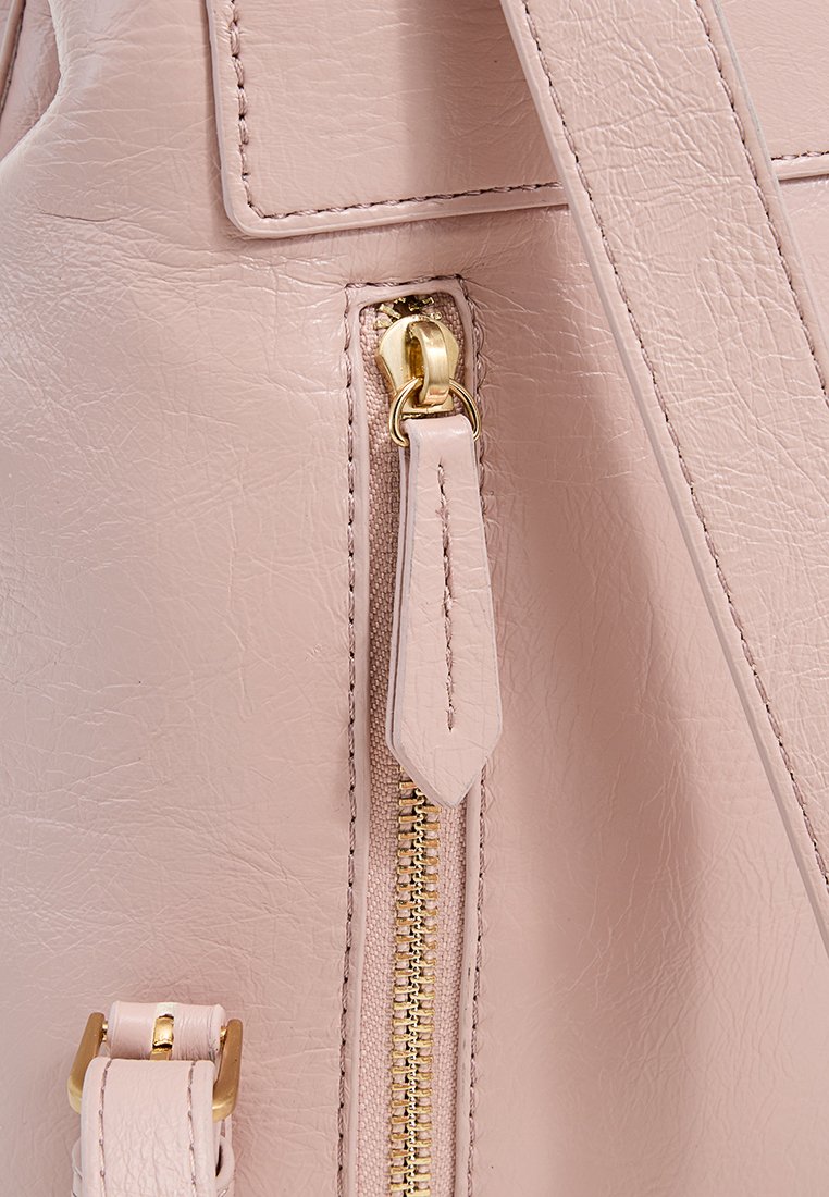 Strukturierte rosa Kunstledertasche mit einem goldenen Reißverschluss und Reißverschlussgriff, ausgestattet mit einem flachen Träger, der an der Seite befestigt ist. Goldene Metallbeschläge.